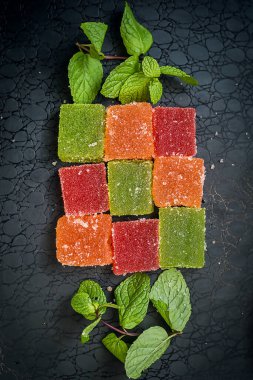 çok renkli marmelat ve siyah arka planda bir tutam nane.