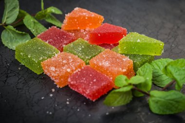 çok renkli marmelat ve siyah arka planda bir tutam nane.