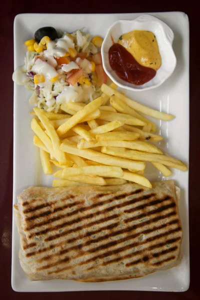 plate with Mexican tacos, French fries, salad and sauces