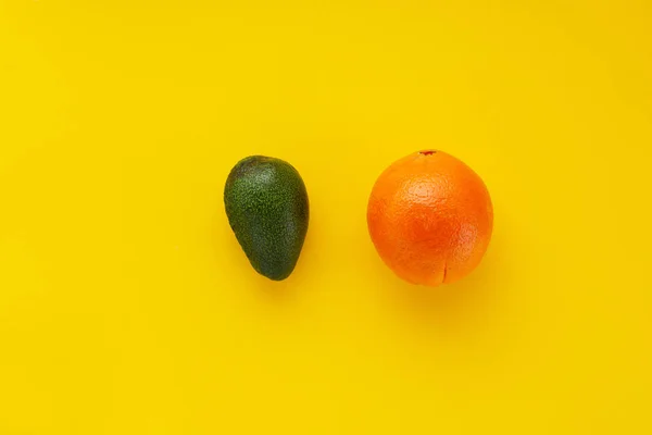コピー スペースと黄色の背景にアボカドとオレンジのフルーツ — ストック写真