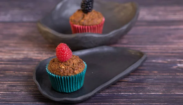 Rustik tarzda ahşap masada ahududu ve siyah kil çanak ile ev yapımı muffin