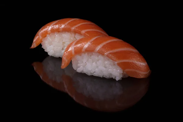 Yansıma ile siyah arka plan üzerinde taze somon ve pirinç ile Close-up Japon gıda suşi