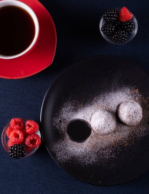 Ev yapımı çikolatalı kek topları truffels siyah plaka ve kırmızı ve siyah ahududu rustik tarzı koyu arka plan ile coffe fincan ile toz şeker serpilir.üst görünümü. Closeup.