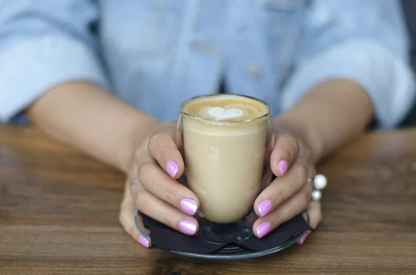 A glass of cappuccino in female hands — Stock Photo, Image