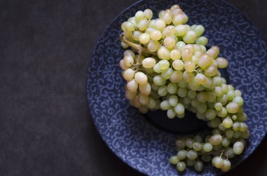 Siyah tabakta bir demet yeşil üzüm  