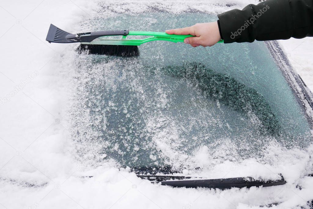 Cleaning the car, windshield brush from snow and ice. Seasonal difficulties on the road.  Caring for transport in the winter. Cleaning the frozen car window.