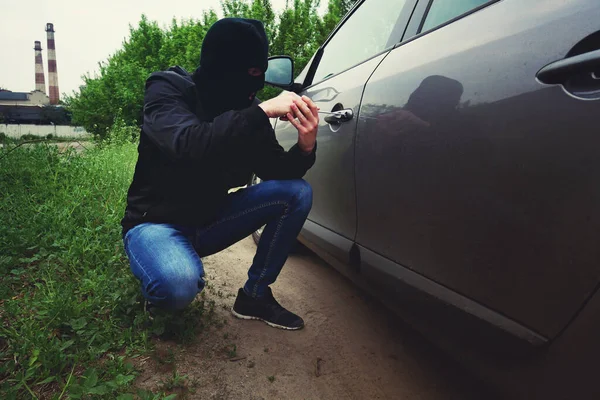 車の盗難だ 車のドアのロックを壊す ドライバでロックを開きます 黒いバラクラバの男泥棒ハイジャッカー — ストック写真