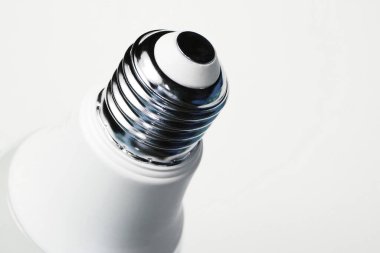 Enerji tasarrufu ekonomik ampulü yaktı. Beyaz arkaplanda lamba ipliği olan metal taban.