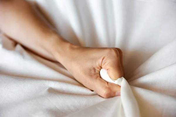 Kadın eli çarşafı sıkar, zevki ve orgazmı simgeler.