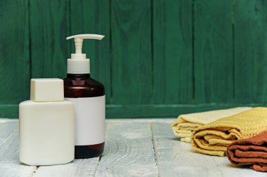 Kavanoz ve şişe kozmetik, ahşap bir rafta havluyla durgun bir hayat.