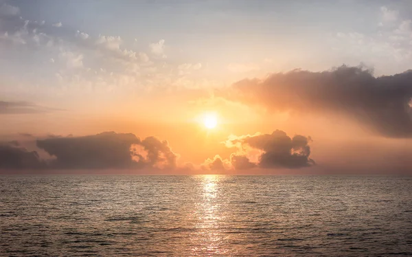 海で日没。太陽が雲の後ろに隠れている. — ストック写真