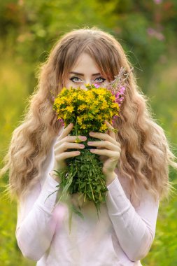 Kız sık çimenlerde oturuyor..