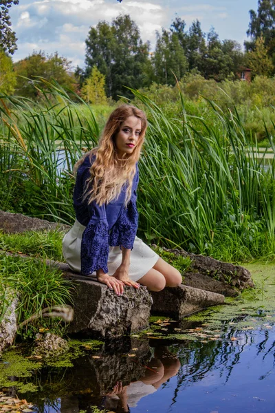 Una Chica Sienta Lago Con Una Mano Cerca Del Agua —  Fotos de Stock