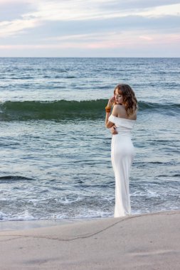 Rusya, Kalininingrad bölgesi, Baltık Denizi 'nde dar beyaz bir elbise içinde. Gece elbiseli kız, sudan seksi çıkıyor, adada düğün..