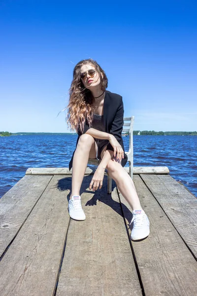 Çirkin su deposu Kalyazin şehrinin arka planında siyah ceketli bir kız. Kaya kıyısı.