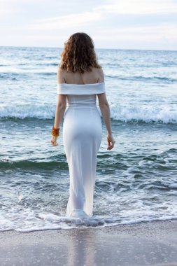 Rusya, Kalininingrad bölgesi, Baltık Denizi 'nde dar beyaz bir elbise içinde. Gece elbiseli kız, sudan seksi çıkıyor, adada düğün..