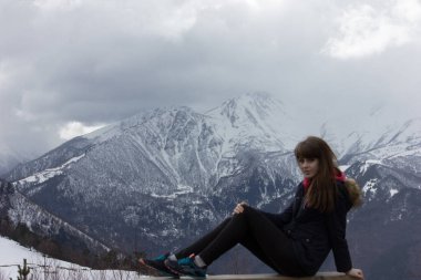 Dağlarda kalın ceketli bir kız. Dombai 'nin karlı dağlarının manzarası.