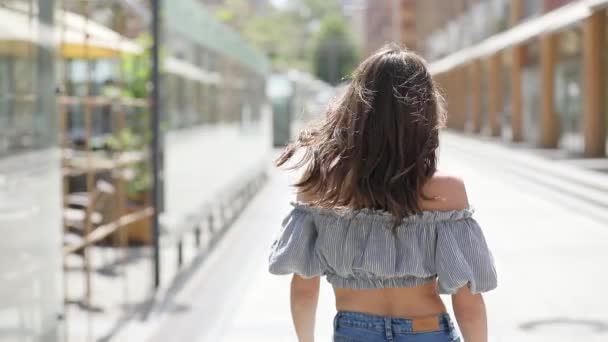 Елегантна брюнетка, що йде вулицею міста і повертає обличчя, кидає волосся — стокове відео
