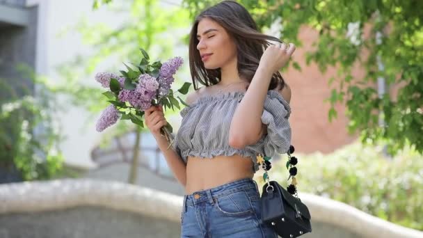 Mujer feliz disfrutando del olor de las flores frescas de lila — Vídeo de stock