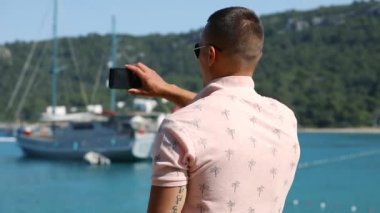 Genç adam olun panoramik fotoğraf veya video smartphone ile deniz sahil yakınında
