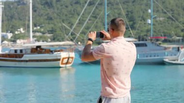 Genç adam olun panoramik fotoğraf veya video smartphone ile deniz sahil yakınında