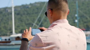 Genç adam olun panoramik fotoğraf veya video smartphone ile deniz sahil yakınında
