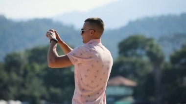 Genç adam olun panoramik fotoğraf veya video smartphone ile çevre beach