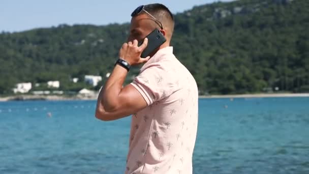 Muž mluví o smartphone poblíž blue sea resort — Stock video