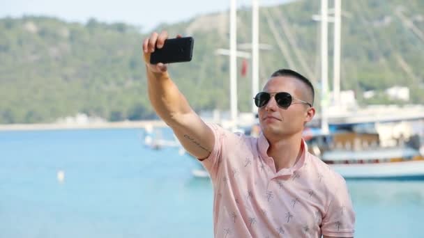 Young man tourist make selfie photo at the sea coast — Stock Video