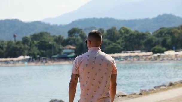 Молодой человек турист уйти глядя на море пляжные горы в Кемере — стоковое видео