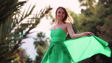 Mutlu kadın yakınındaki tropikal palmiye ağaçları yeşil giysili poz