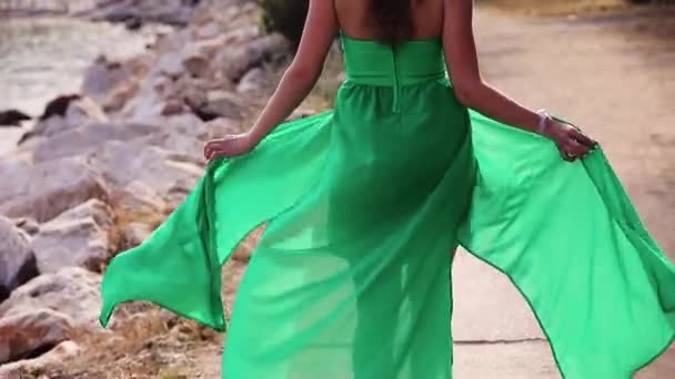 Женщина гуляет по пляжу и позирует в зеленом платье, вид сзади — стоковое видео