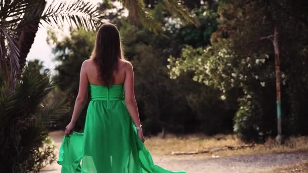 Женщина идет по пляжу и позирует в зеленом платье — стоковое видео
