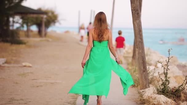 Belle femme s'en va sur la plage en robe verte, vue arrière — Video