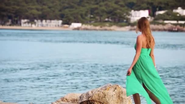 Hermosa mujer en vestido verde mirando al paisaje de la costa del mar — Vídeos de Stock