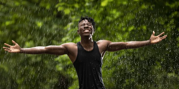 African Man Enjoying Fresh Summer Rain While Hands Raised — Stock Photo, Image