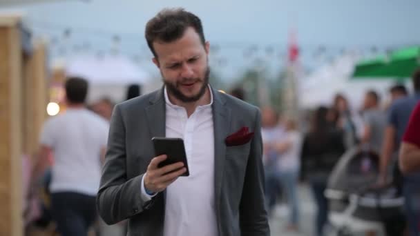 Hombre barbudo feliz en traje clásico caminando mirando al teléfono inteligente — Vídeo de stock