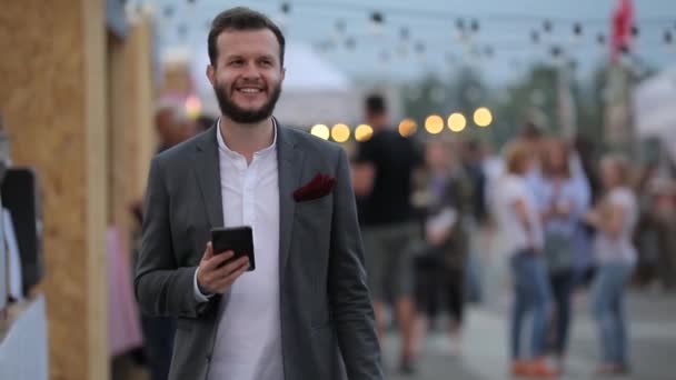 Hombre barbudo feliz en traje clásico caminando mirando al teléfono inteligente — Vídeo de stock