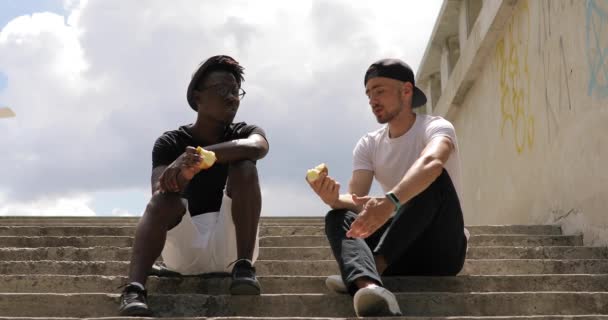 Amigos varones sentados y comiendo manzanas, comiendo bocadillos — Vídeos de Stock