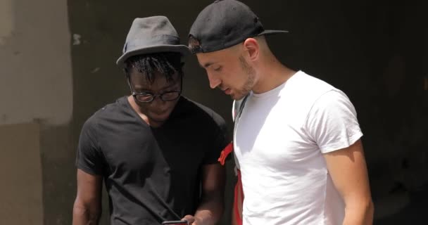 도시에서 걷는 스마트폰 사진을 보고 행복 한 남성 multiracial 친구 — 비디오