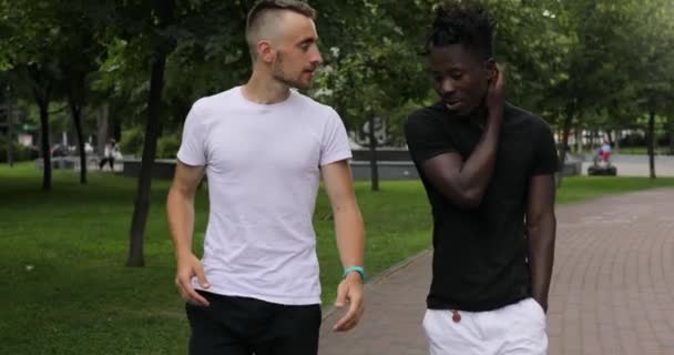 Male friends walking together under rain and talking — Stock Video