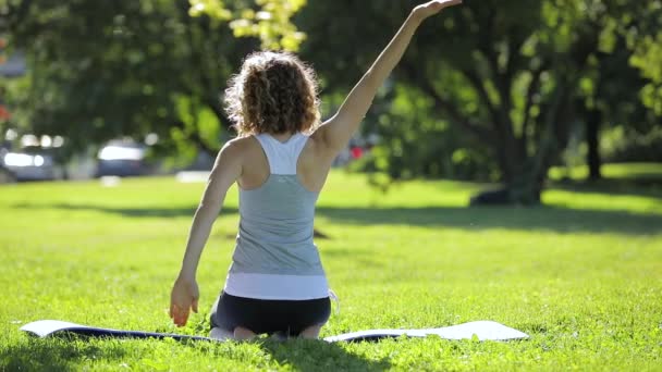 Woman exercising yoga in park on beautiful day — Stock Video
