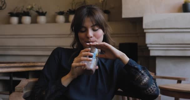 Menina feliz positivo em um café bebendo frappe com gelo olhando para mim — Vídeo de Stock