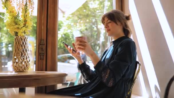 Счастливая девушка отдыхает в кафе, улыбается и разговаривает — стоковое видео