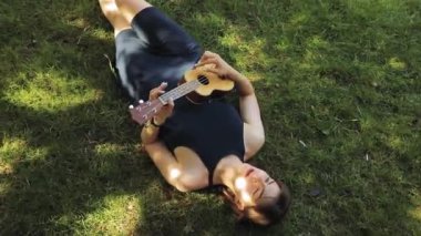 Genç kadın dinlenme, o oyun gitar, gitar, çim üzerinde yalan
