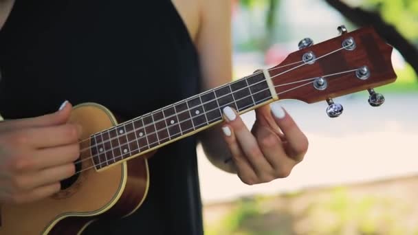 Genç bir kadın ukulele çalıyor, izin günlerinde gitar çalıyor. — Stok video