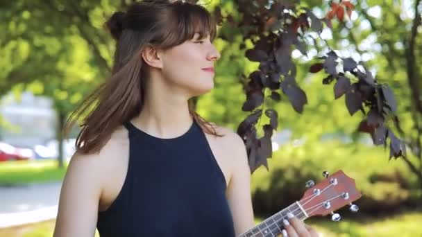 Mujer joven tocar en ukelele, pequeña guitarra en día libre — Vídeo de stock