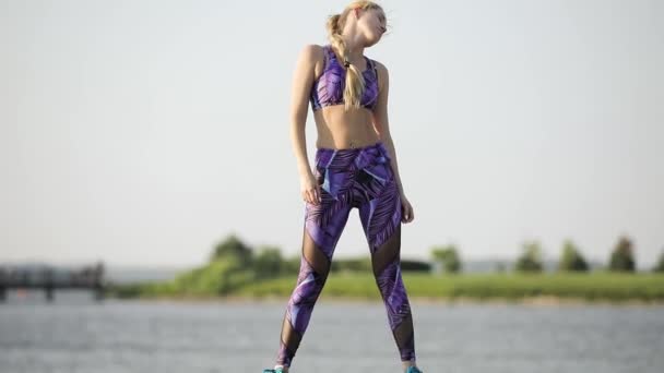 Женщина в спортивной одежде согревается на открытом воздухе, растягивает мышцы — стоковое видео