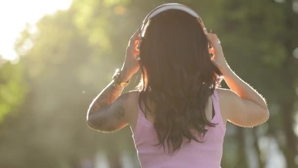 Femme tatouée de style grunge écoutant de la musique dans de gros écouteurs, vue arrière — Video