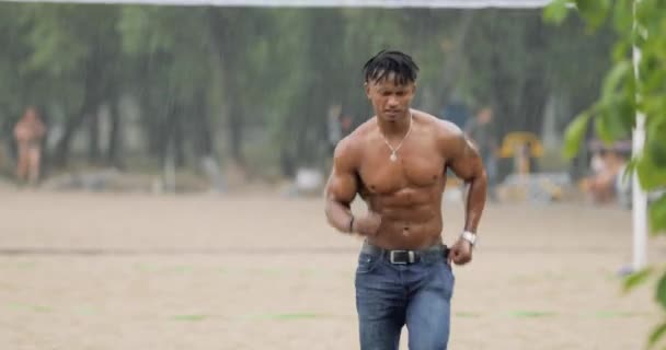 Σέξι άνδρας φαλλοκρατών με μυώδες σώμα που τρέχει στην παραλία κάτω από βροχή — Αρχείο Βίντεο